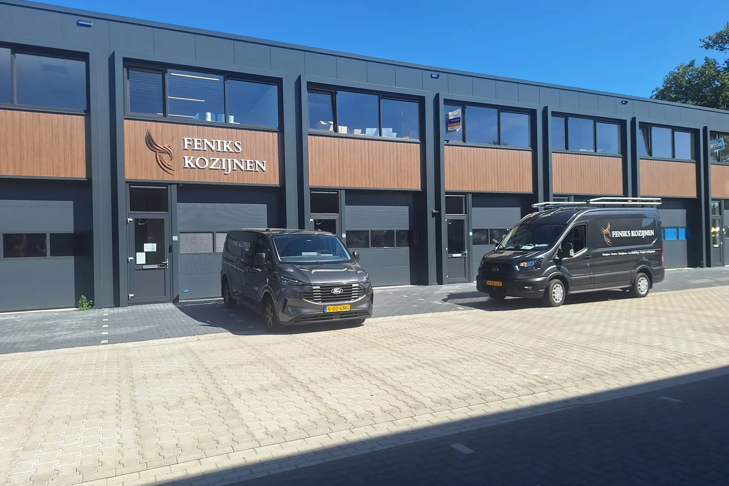 Het bedrijfspand van Feniks Kozijnen aan de Lage Kamp in Apeldoorn, met beide bussen ervoor